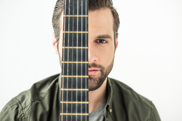 Close up of man face behind guitar fretboard