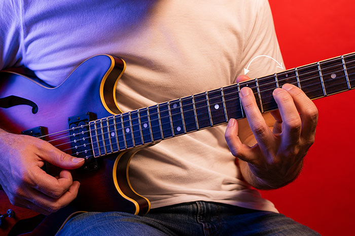 Male guitarist sitting on chair and his hand playing legato technique